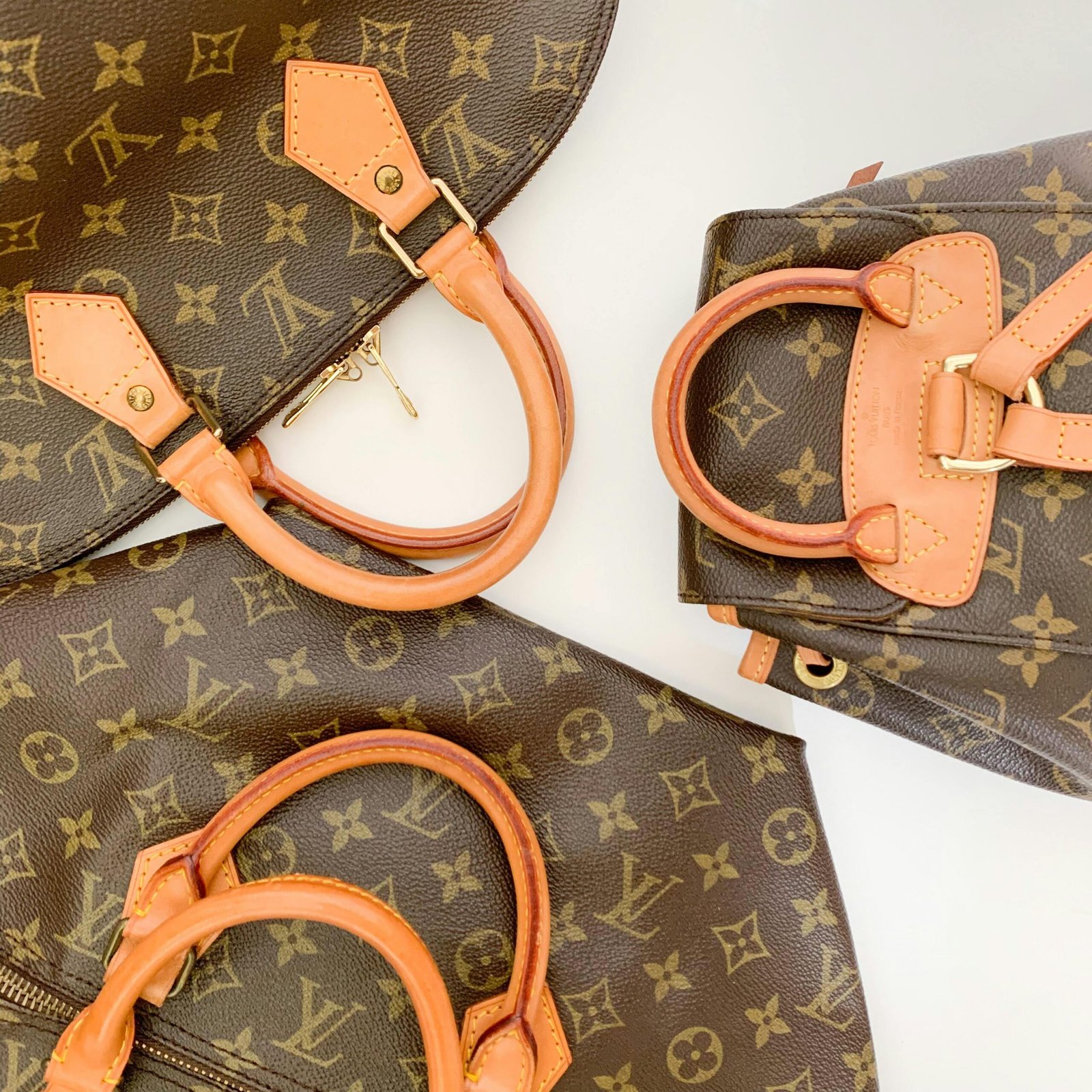 High-end designer leather handbags with monogram pattern lay elegantly displayed.