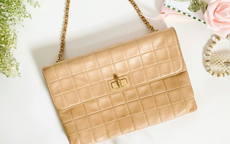 Stylish beige quilted purse with a chain strap, perfect for fashion enthusiasts.
